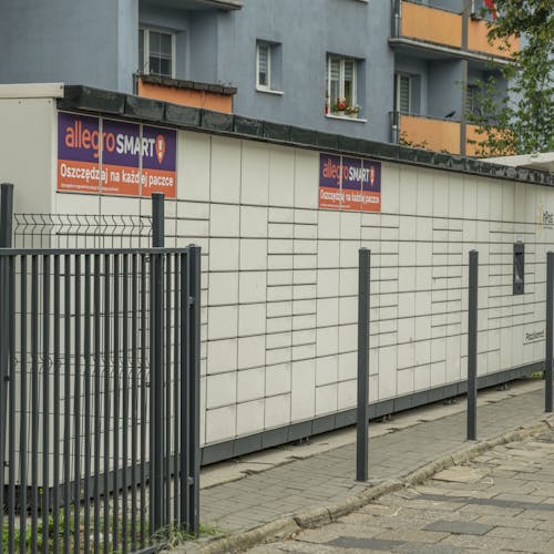 Outdoor parcel locker in Wroclaw, with Allegro Smart advertisement, near residential buildings.