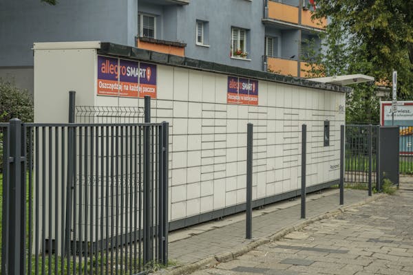 Outdoor parcel locker in Wroclaw, with Allegro Smart advertisement, near residential buildings.